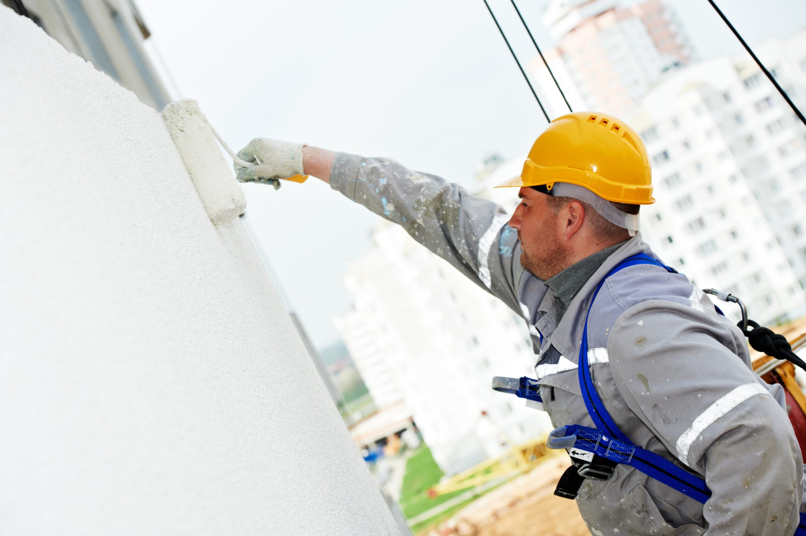 Worker applying protective coating to the exterior wall of a residential home