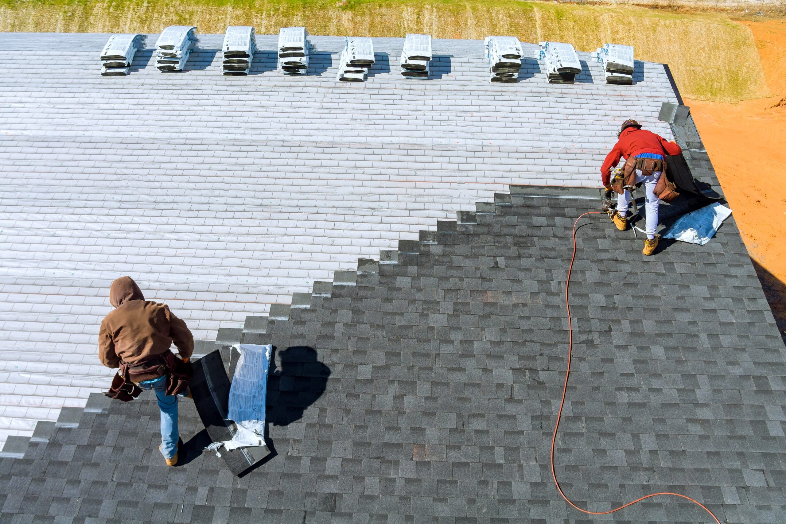 Construction worker installing new roof shingles on a residential home
